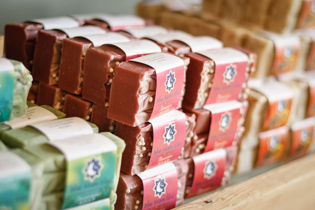 An assortment of wrapped Blue Moon Elise handmade soap bars on a wooden shelf